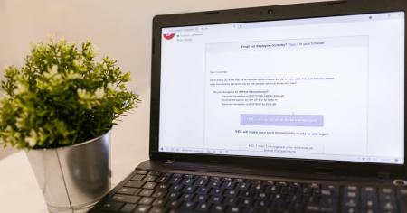 A black laptop sitting on a table displaying an email message regarding fraudulent behavior.