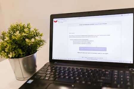 A black laptop sitting on a table displaying an email message regarding fraudulent behavior.