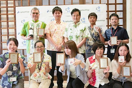 Splashtop team members smiling and holding awards, dressed in colorful attire with a Splashtop backdrop